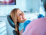 Woman in treatment chair smiling at dental hygienist