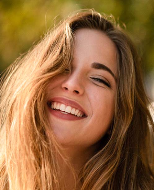 young woman smiling after getting dental bridge in Denver