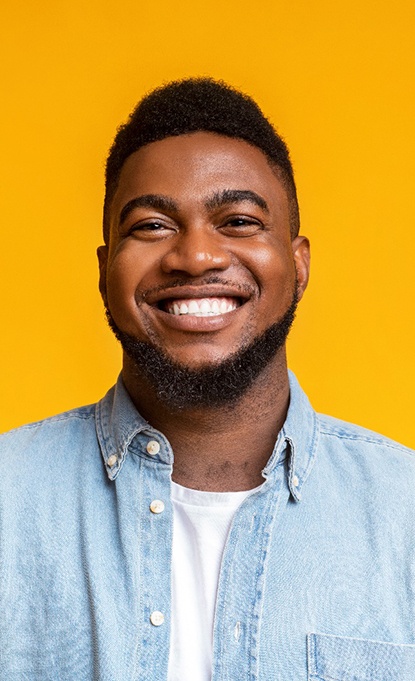 confident man smiling in front of a yellow background