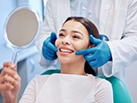 woman looking in the mirror with the dentist next to her