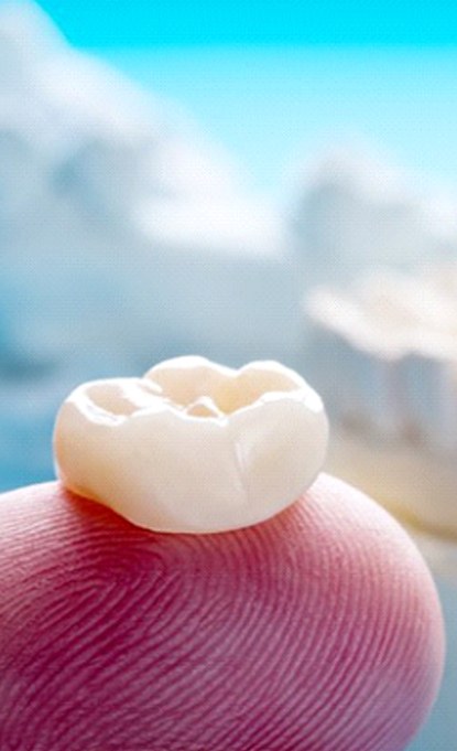 Closeup of dental crown in Denver on finger