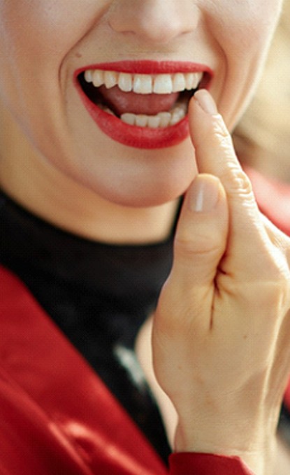 Woman smiling and pointing to dental crown in Denver