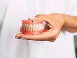 dentist holding a set of full dentures 