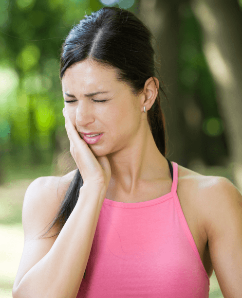 Woman in need of emergency dentistry holding cheek in pain