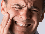Man with head neck and jaw pain holding face in pain