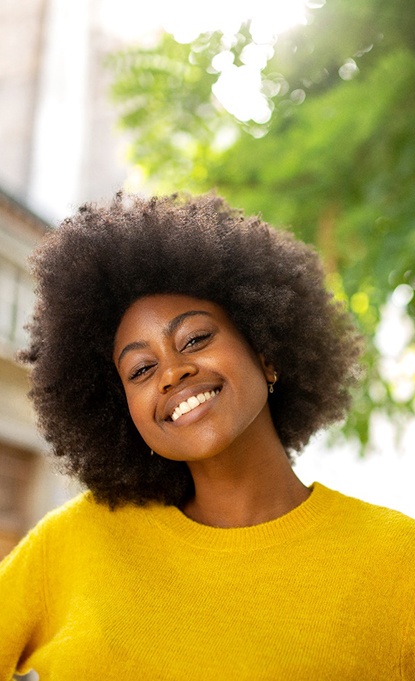 Smiling woman outside with dental implants in Denver, CO