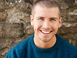 Man with dental implants in Denver, CO in front of stone wall