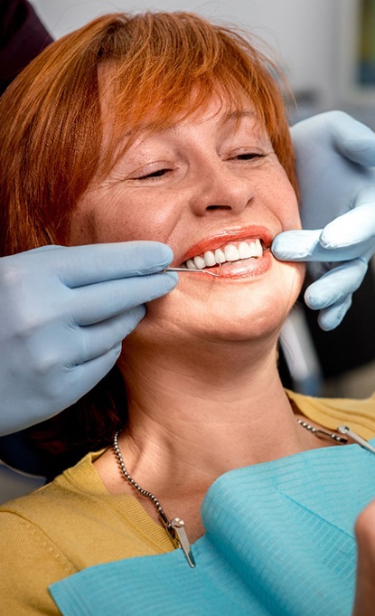 Female patient checking smile after getting dental implants in Denver, CO