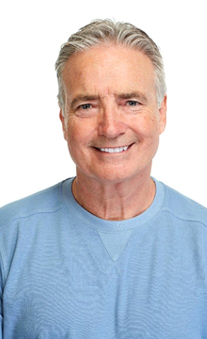 Older man in blue shirt smiling with white background