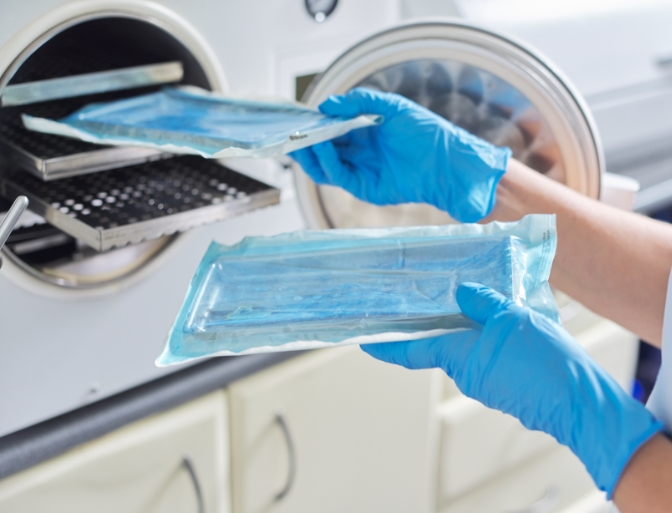 Dental team member placing sealed and sanitized dental tools in storage case