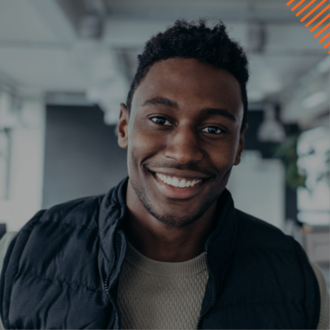 Young man in black vest smiling in an office