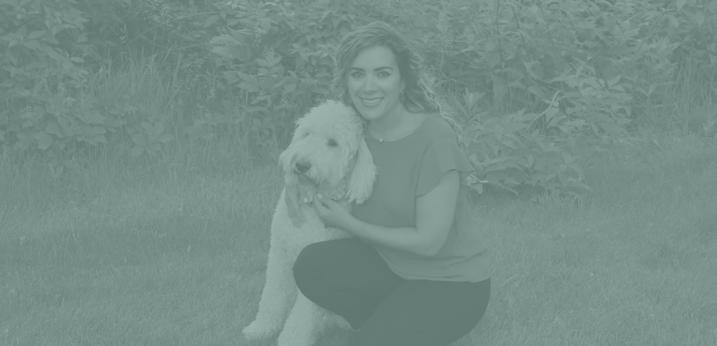 Dr. Shauna Soltani, a dentist, kneels in the grass with a dog, highlighting a serene outdoor moment.