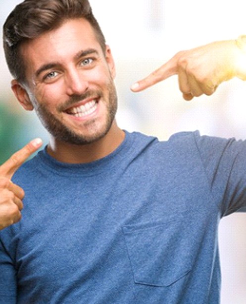 man pointing to his smile after getting teeth whitening in Denver, CO