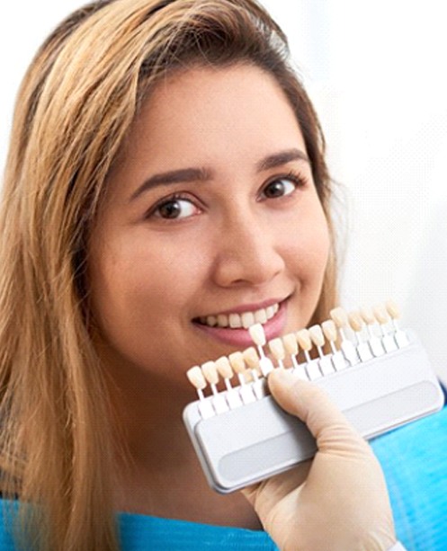 dentist holding a row of veneers in Denver to a patient’s smile