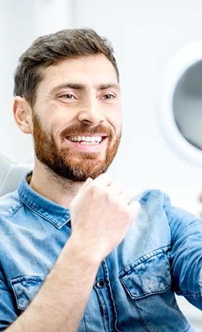 dental patient admiring his smile in a mirror after getting veneers
