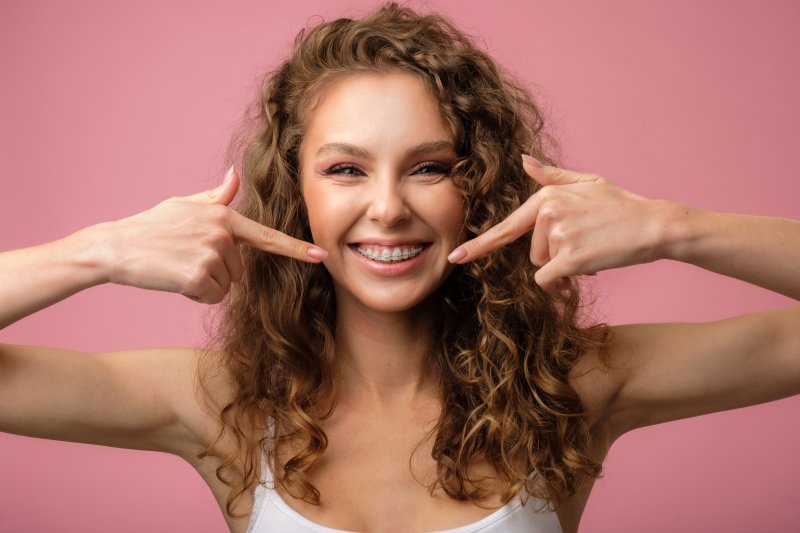 young woman smiling and pointing to braces