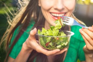 a woman showing her white teeth while eating healthy foods