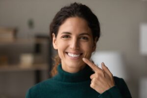 Woman smiling and pointing to her veneers